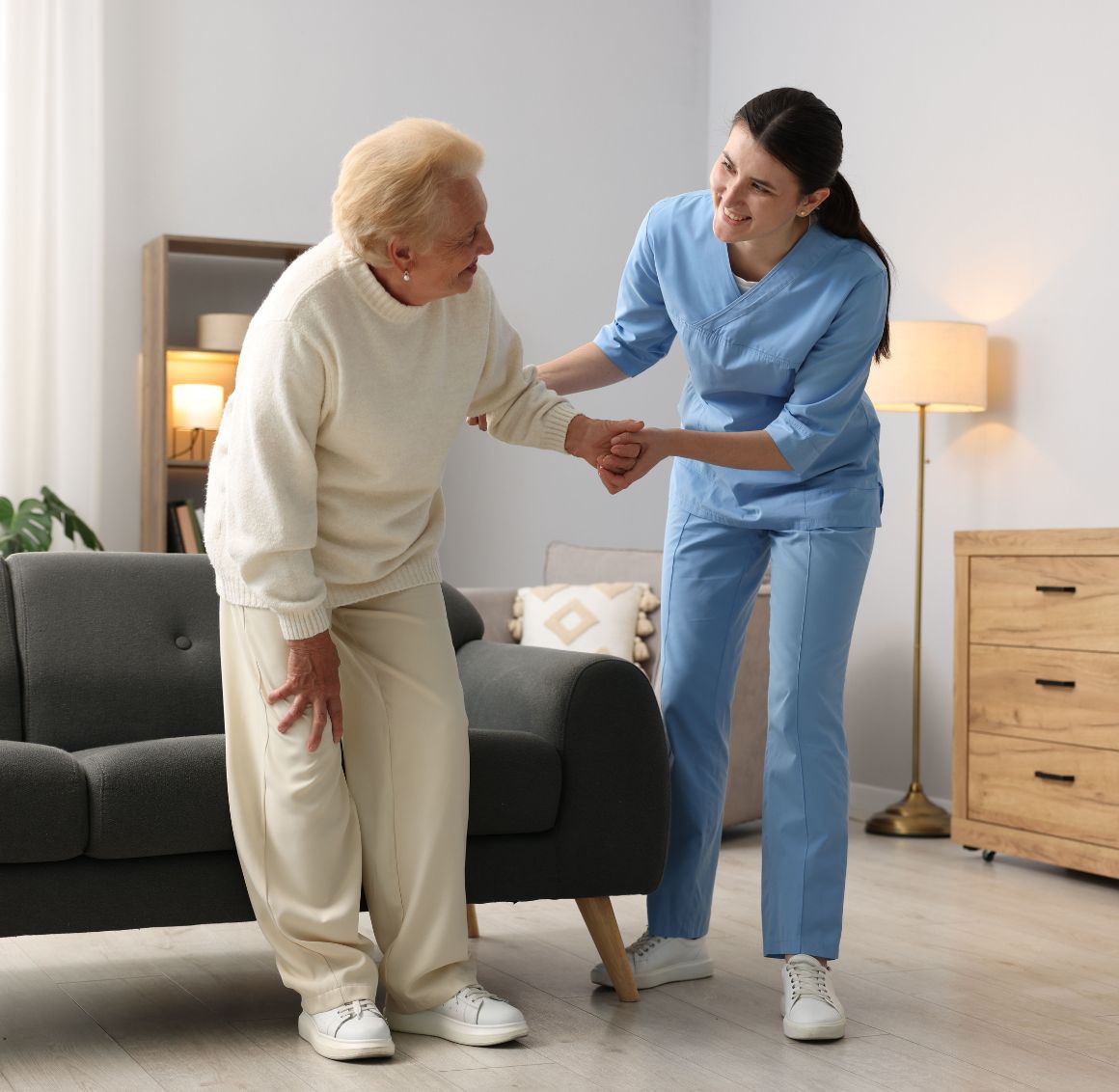 Light Housekeeping in Temple Terrace (1) A caregiver assisting an elderly woman with standing up safely from a chair, providing hands-on support during mobility care in a comfortable home setting in Temple Terrace.
