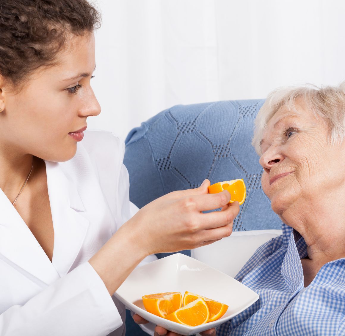 Meal Preparation in Temple Terrace (1) A caregiver offering fresh fruit to an elderly woman, providing gentle feeding support and companionship as part of home care in Temple Terrace.