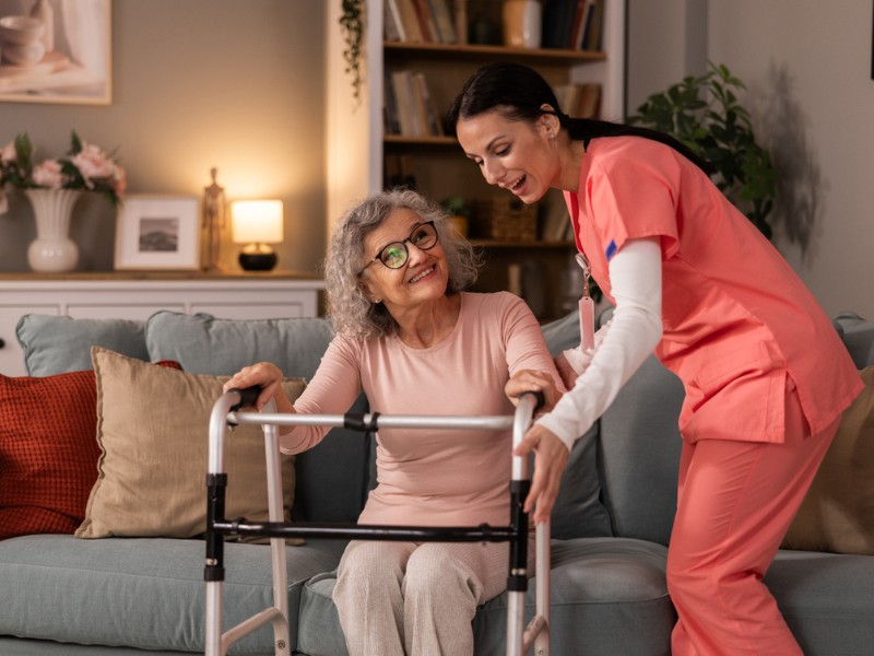 Live-In & 24 Hour Care in Stamford, CT | Home Assistance A cheerful caregiver assisting a senior woman with her walker, highlighting reliable live-in and 24 hour care in Stamford, CT.